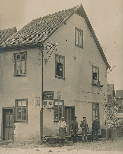 Bild von 1900 der Schmiede in Höchst mit Philipp Thierolf, Gesellen und Lehrling vor dem Haus.